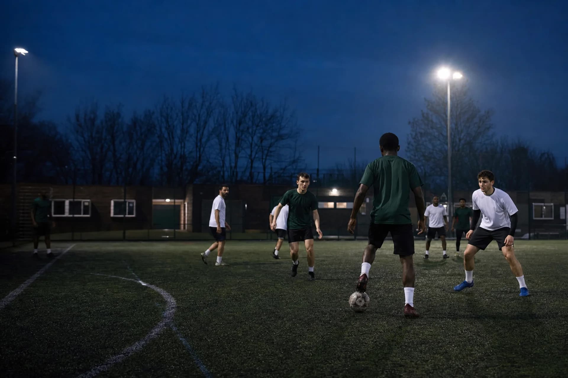 Fictional adult grassroots players training under floodlights